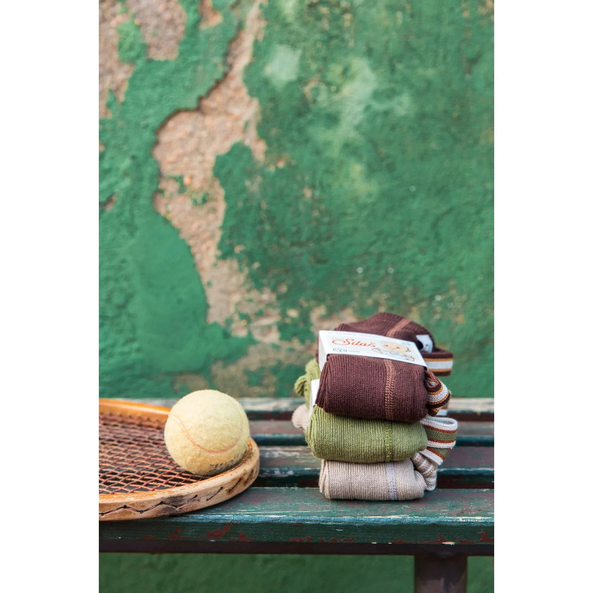 Gestapelte gefaltete Socken neben Strumpfhose mit Träger in olivgrün gestreift