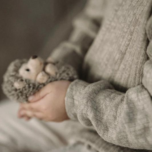 Kuscheltiermaus in der Hand eines Kindes neben dem Produkt Sweater Strick olive