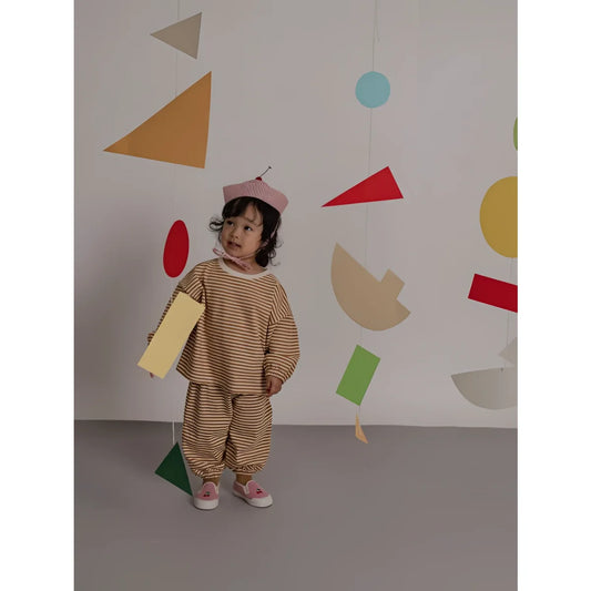 Kind trägt ein sweatshirt copper stripes in kupferfarben mit braun-creme gestreiftem zweiteiler und rot-weiß kariertem hut