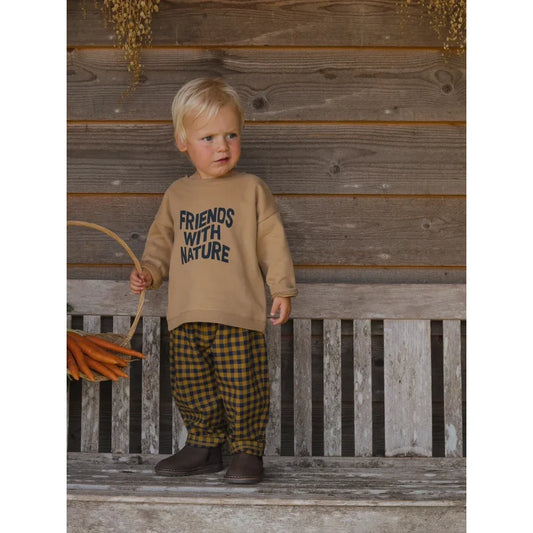 Ein Kleinkind trägt einen beigen Friends with Nature Sweatshirt und karierte Hose
