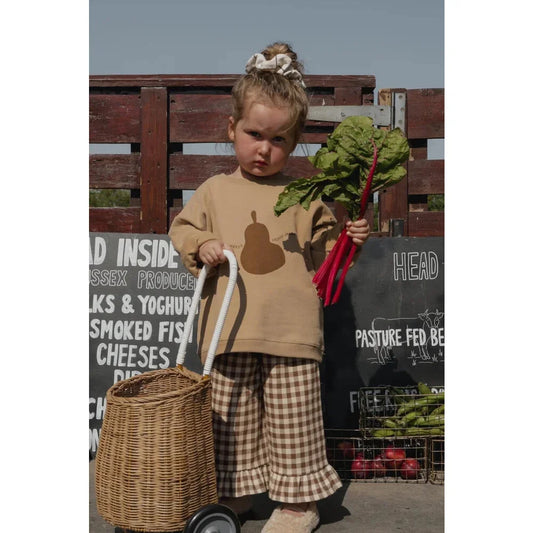 Junger Mensch hält einen Strauß Blattgemüse und einen Korb, trägt ein Sweatshirt