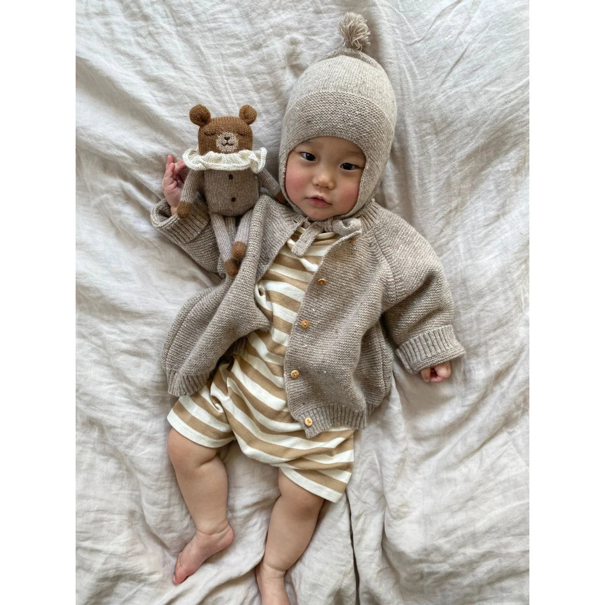 Neugeborenes mit neutraler gestrickter Mütze, Cardigan und Streifen-Body mit Teddy