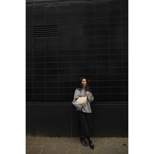 Frau in grauem Pullover und schwarzen Hosen mit weißem Objekt, Teddy Fanny Pack