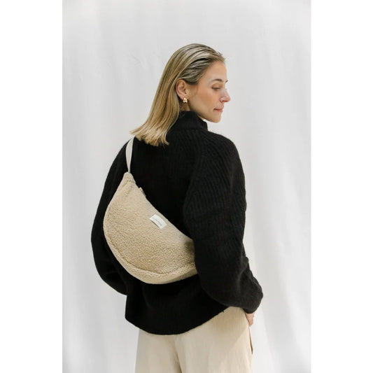 Beige, fuzzy, crescent-shaped Teddy Adult Fanny Pack in Ecru worn crossbody