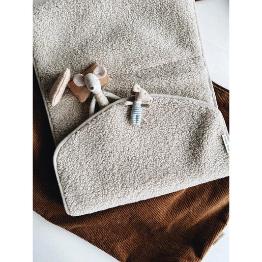Weiches graues Handtuch mit kleinen Holzspielzeugen auf Teddy Wickelunterlage Ecru