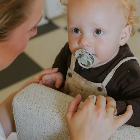 Ein hellgrauer round latex schnuller mit texturierter oberfläche und weicher silikonnuckel ideal für ökologische baby- & kinderprodukte