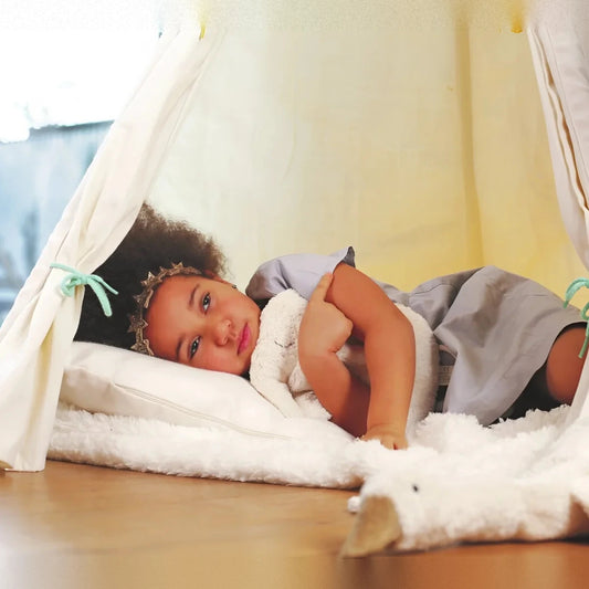 Girl relaxing in a tipi with the animal pillow elephant