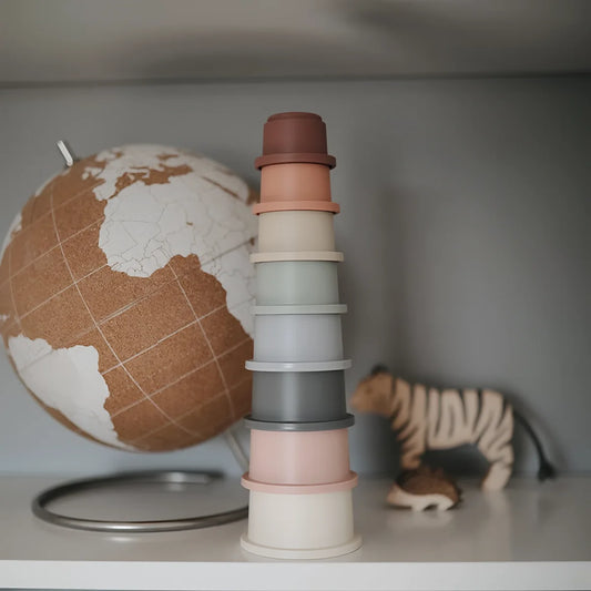 Ein stapel pastellfarbener silikon stapelbecher in gedeckten terrakotta, pfirsich, grau und creme tönen im toy gift box set