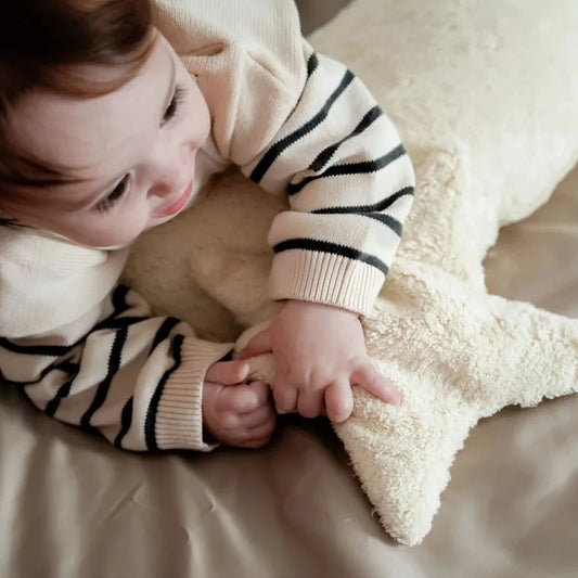 Baby hugging a star heat pad in vanilla