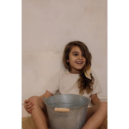 Junge Frau sitzt mit einem Metall-Eimer zwischen den Beinen im Waffle Boxy T-Shirt