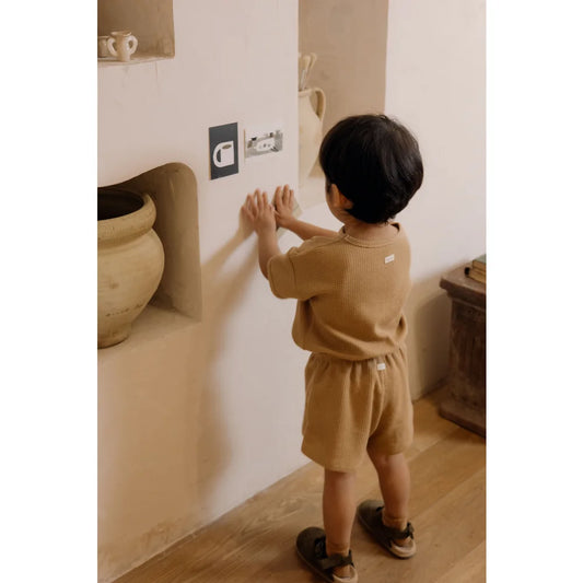 Junger Mensch berührt eine Wandsteckdose in einem Waffel Boxy T-Shirt Claypot