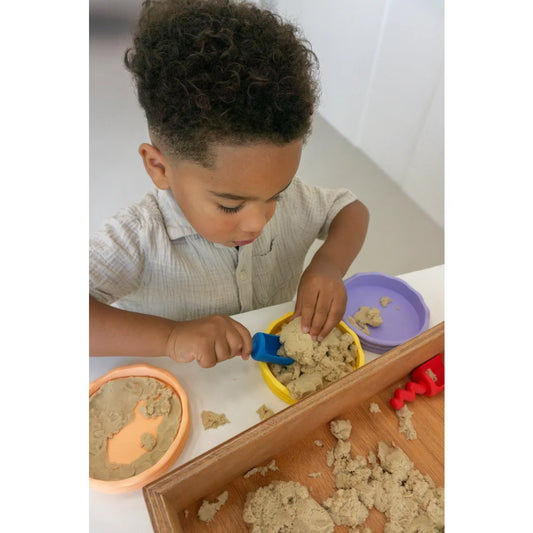 Junge spielt mit Kinetic Sand und Spielzeug, ideal für Little Botanic Label Produkte