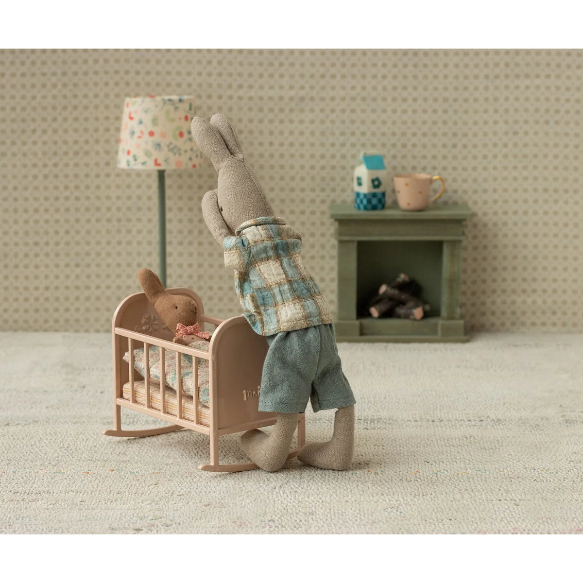 Weiches graues Plüschkaninchen in Wiege My Light rose kniet bei rosa Schaukelwiege