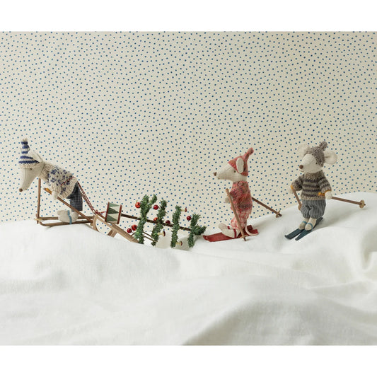 Drei Spielzeugmäuse mit Skiset beim Skifahren neben einem Weihnachtsbaum