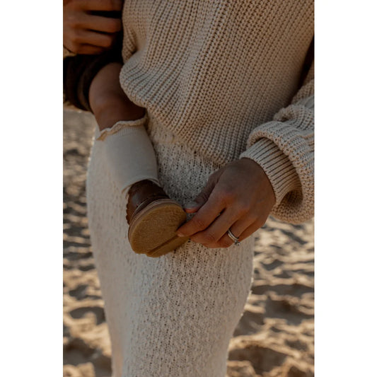 Händchen halten eine Muschel, während ein cremiger Strickpullover getragen wird