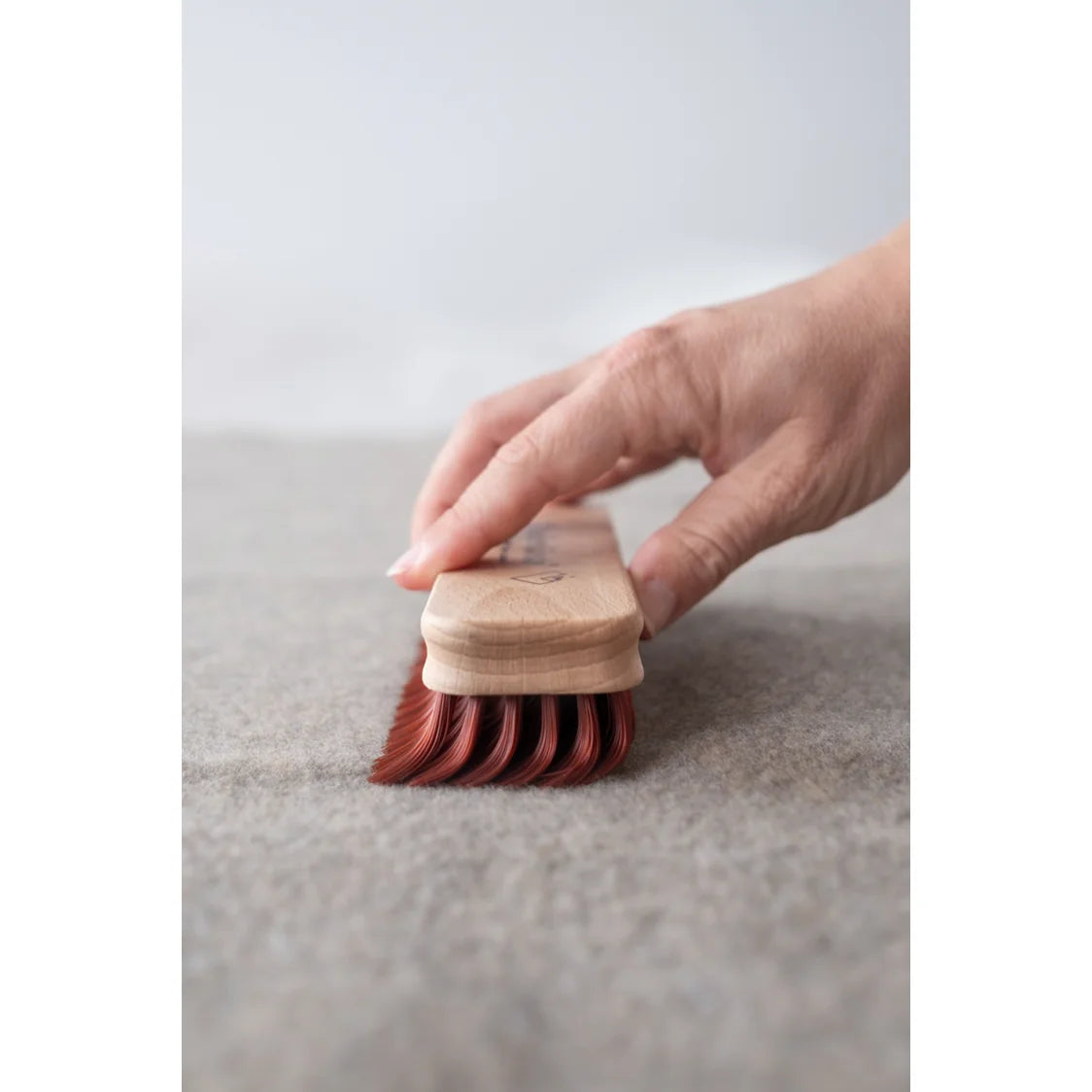 Hand hält Wunderbürste mit rotbraunen Borsten aus Holz