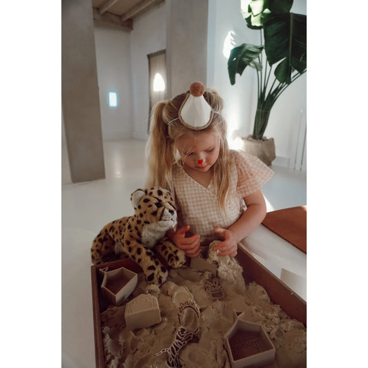 Junge mit Zirkus-Spielset, spielt mit magischem Sand und Cheetah-Plüsch in der Schweiz