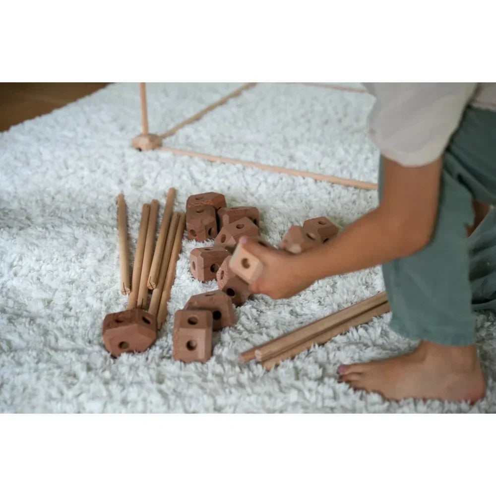 Holz- und Tonbauklötze auf einem weißen Teppich für kreatives Spielen von Kindern.