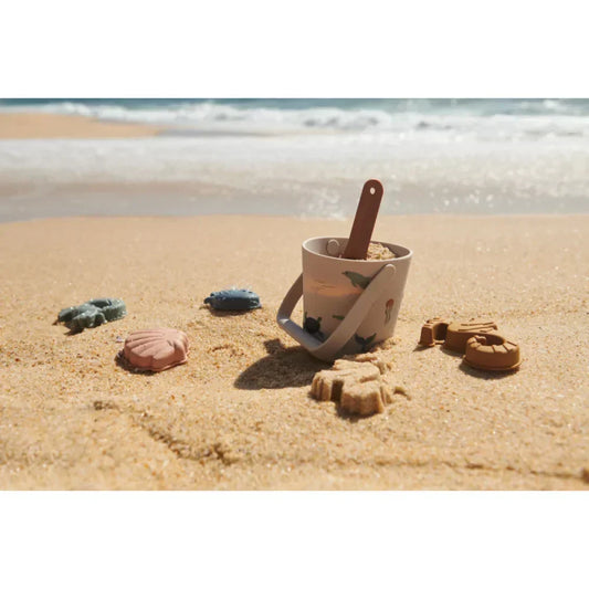 Strandspielzeug auf Sand in einem Artikel über nachhaltige Kindermode von LIEWOOD