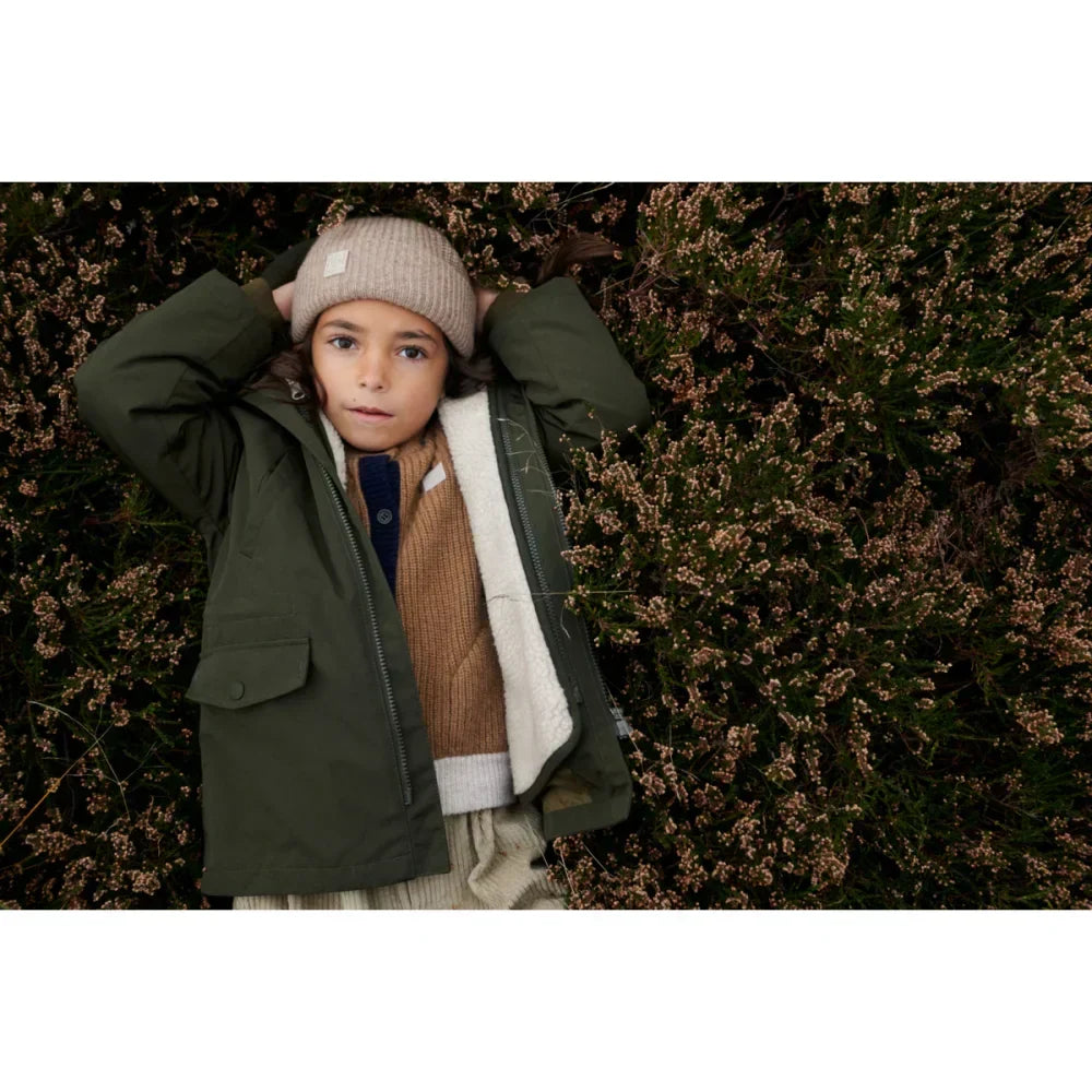 Kind eines Kindes in olivgrüner Timber 2-in-1 Jacke mit Sherpa-Futter und Beanie
