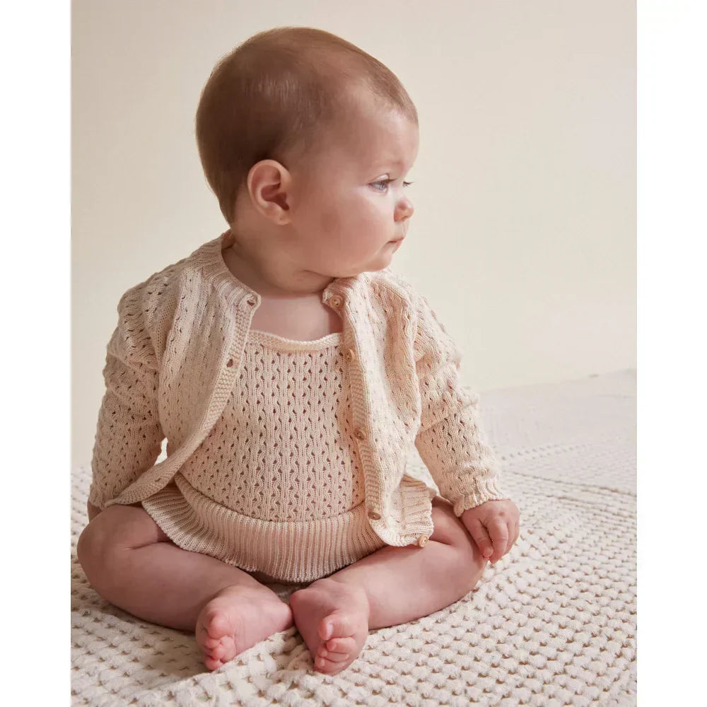 Baby im gestrickten Overall und Cardigan in zeitloser Kindermode für Fashionistas.