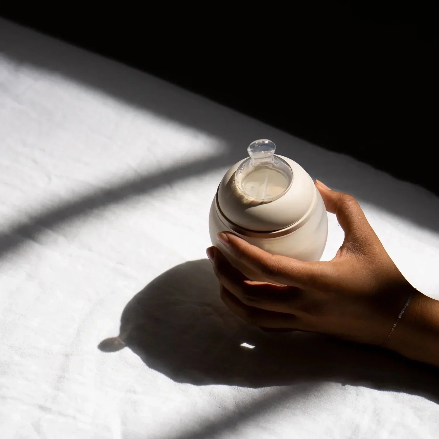 Ein elegante off-white keramik babyflasche mit transparentem glasnippel und goldrand für ökologische baby- & kinderprodukte