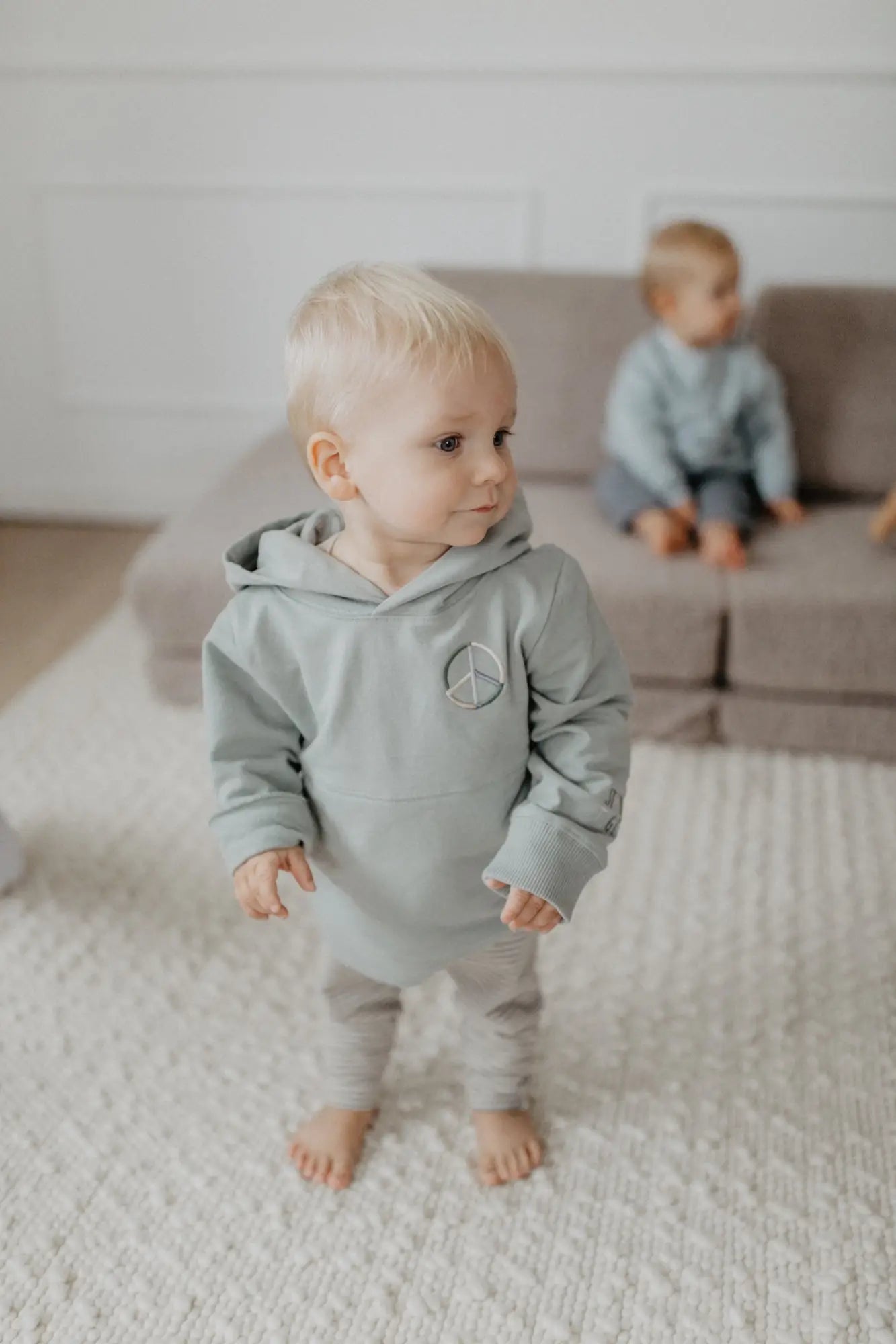 Baby in hellgrünem Kapuzen-Longsleeve mit Peace-Zeichen und passender Hose aus der Sammlung LEEVJE