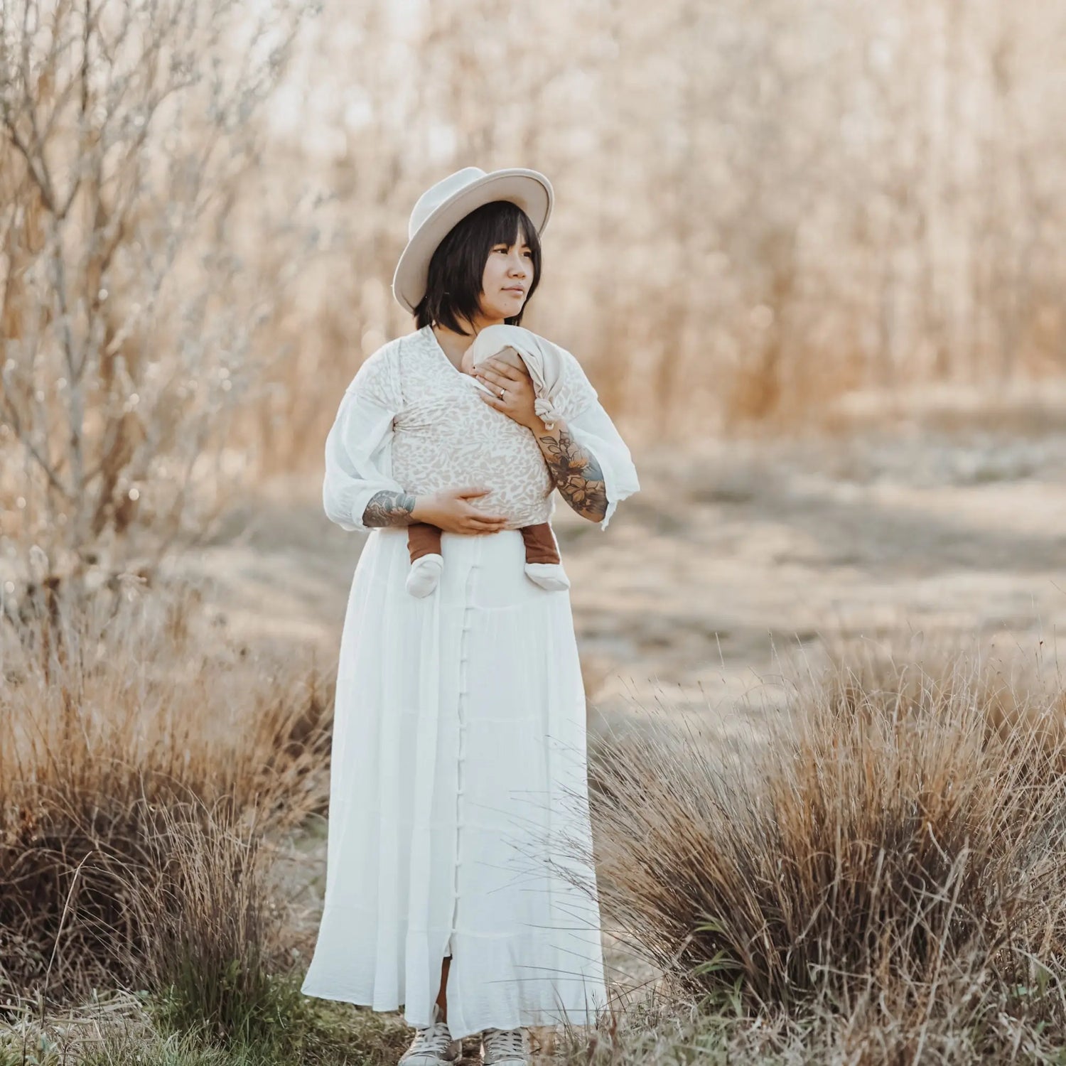 Person in braunem Beanie und Strickpullover liegt auf Herbstblättern in LITTLE WOMBAT Sammlung