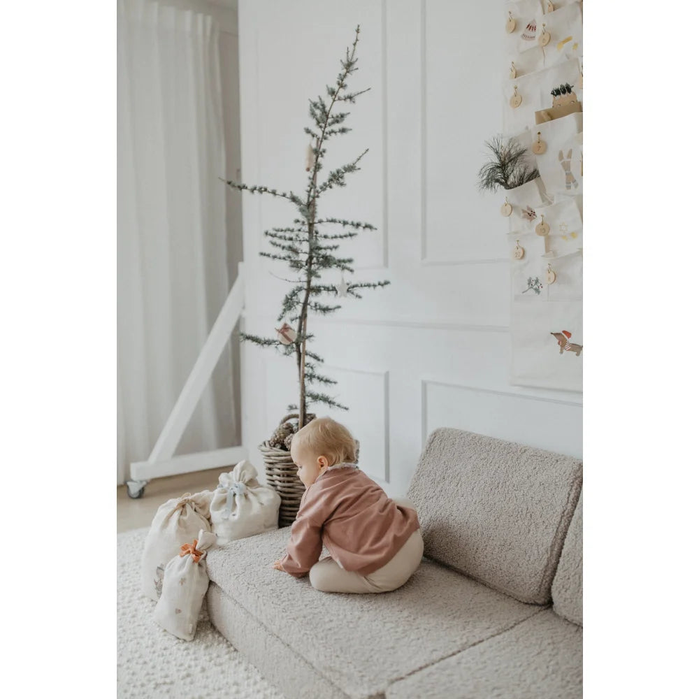 Baby in pink Shirt und weiße Hose krabbelt auf hellgrauem Sofa bei 3er Set Musselin Geschenksäcke Christmas