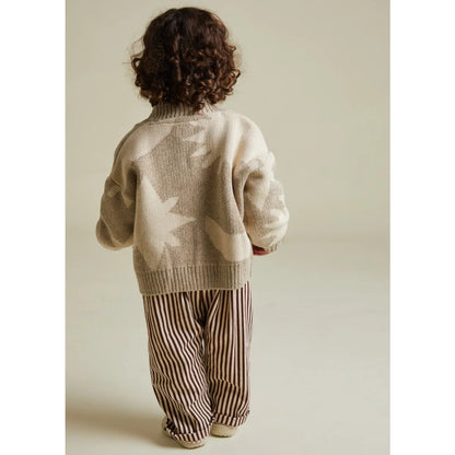 Kind wechselt weichen beigen Strick-Cardigan mit Mond-Stern-Mustern