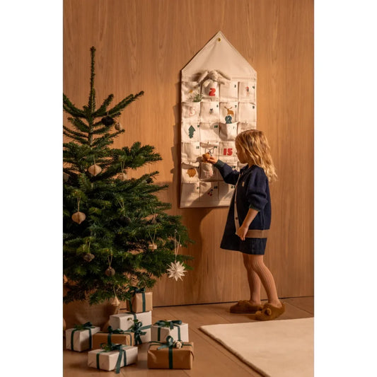 Junge Mädchen interagiert mit Adventskalender Babbo Holiday Sandy neben Weihnachtsbaum