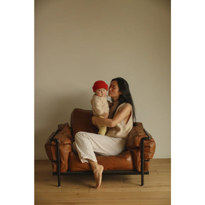 Mama hält Baby in braunem Ledersessel, trägt den Adult Vest Helle Cream