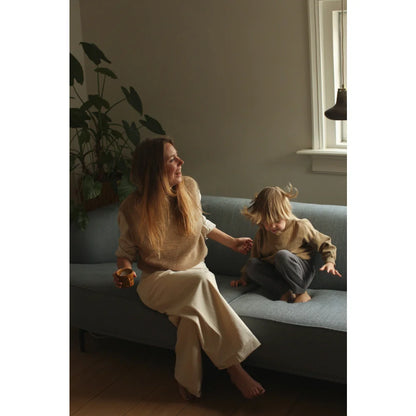 Frau und Kind sitzen auf hellblauem Sofa mit Adult Vest Helle Sand