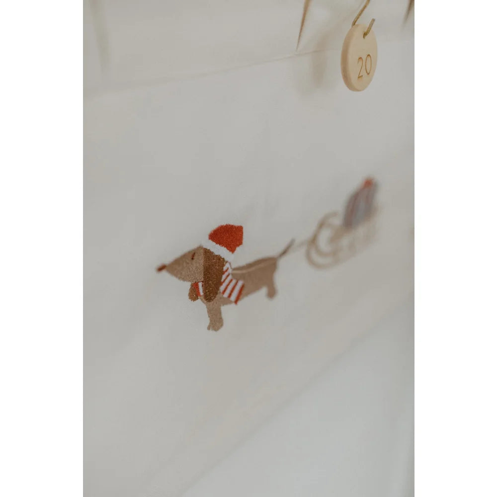 Gestickter festlicher Dackel mit Santa-Hut und Streifenschal zieht Schlitten