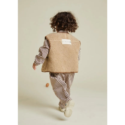 Beige Lammfellweste mit einem weißen Etikett auf dem Rücken, auf dem ’claudie’ steht.