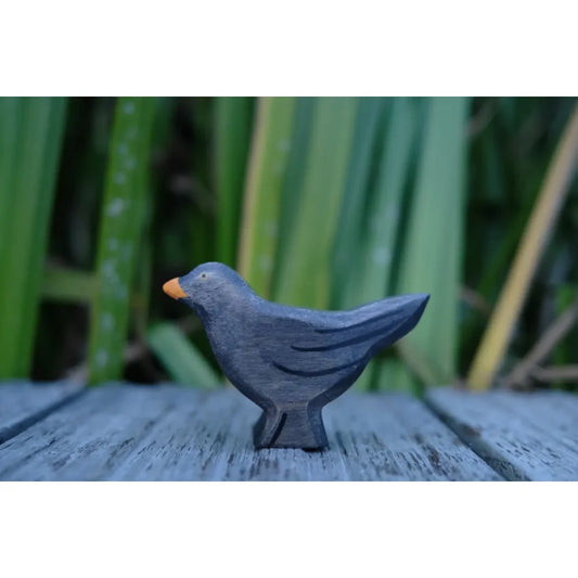 Schwarze Amsel-Figur aus Holz oder Keramik mit orangem Schnabel und Füßen