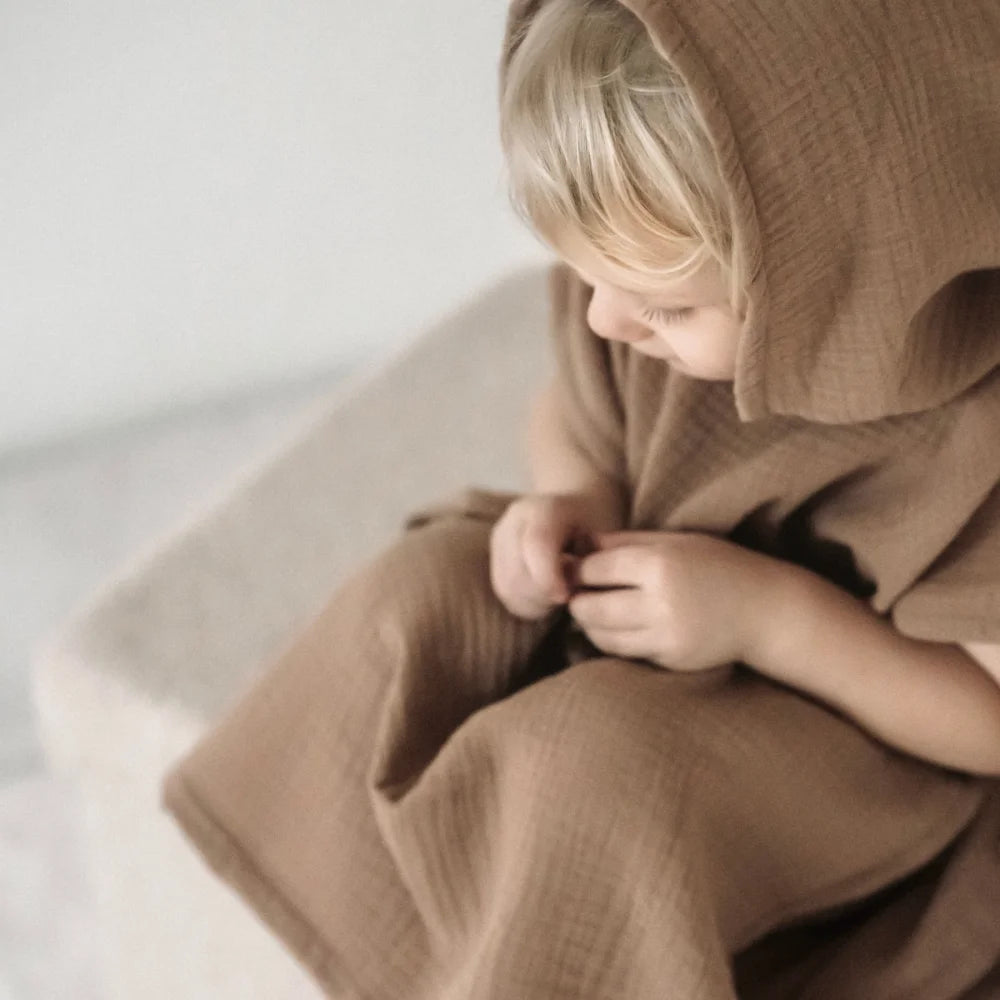 Kind in übergroßem beigem Hoodie, dargestellt im Badeponcho Musselin in verschiedenen Farben