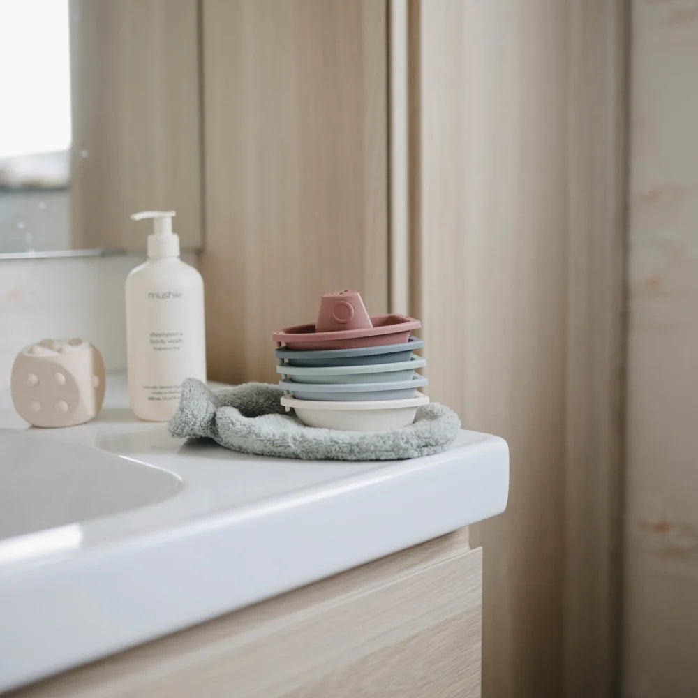 Bunte Keramikschalen auf einem gefalteten Tuch neben Badespielzeug Boote Original