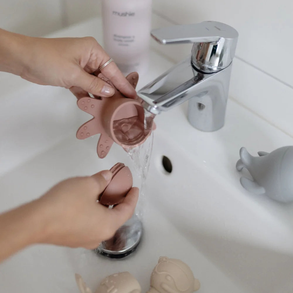 Menstruationshygiene mit Menstruationstasse unter fließendem Wasser im Badezimmer