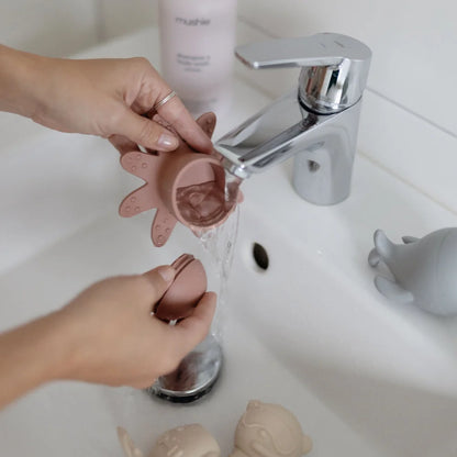 Menstruationshygiene mit Menstruationstasse unter fließendem Wasser im Badezimmer