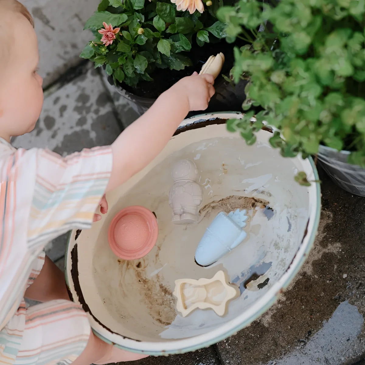 Ein kind hält eine beige, leicht beschädigte keramikschale mit badespielzeug space schimmelresistent und bunten plastikspielzeugen
