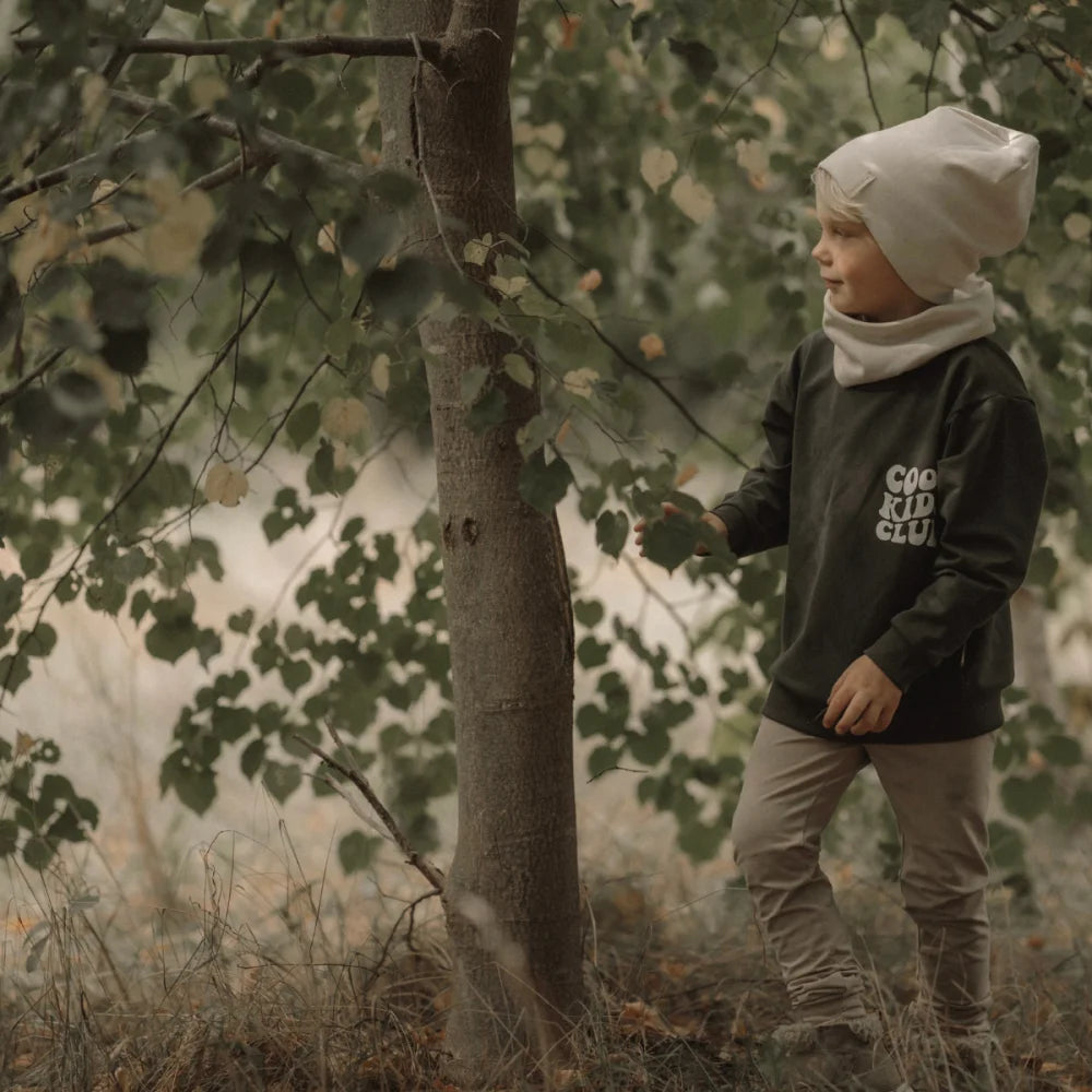 Junges Kindermodell mit Ecru Beanie, dunkel Langarmshirt und leichter Hose