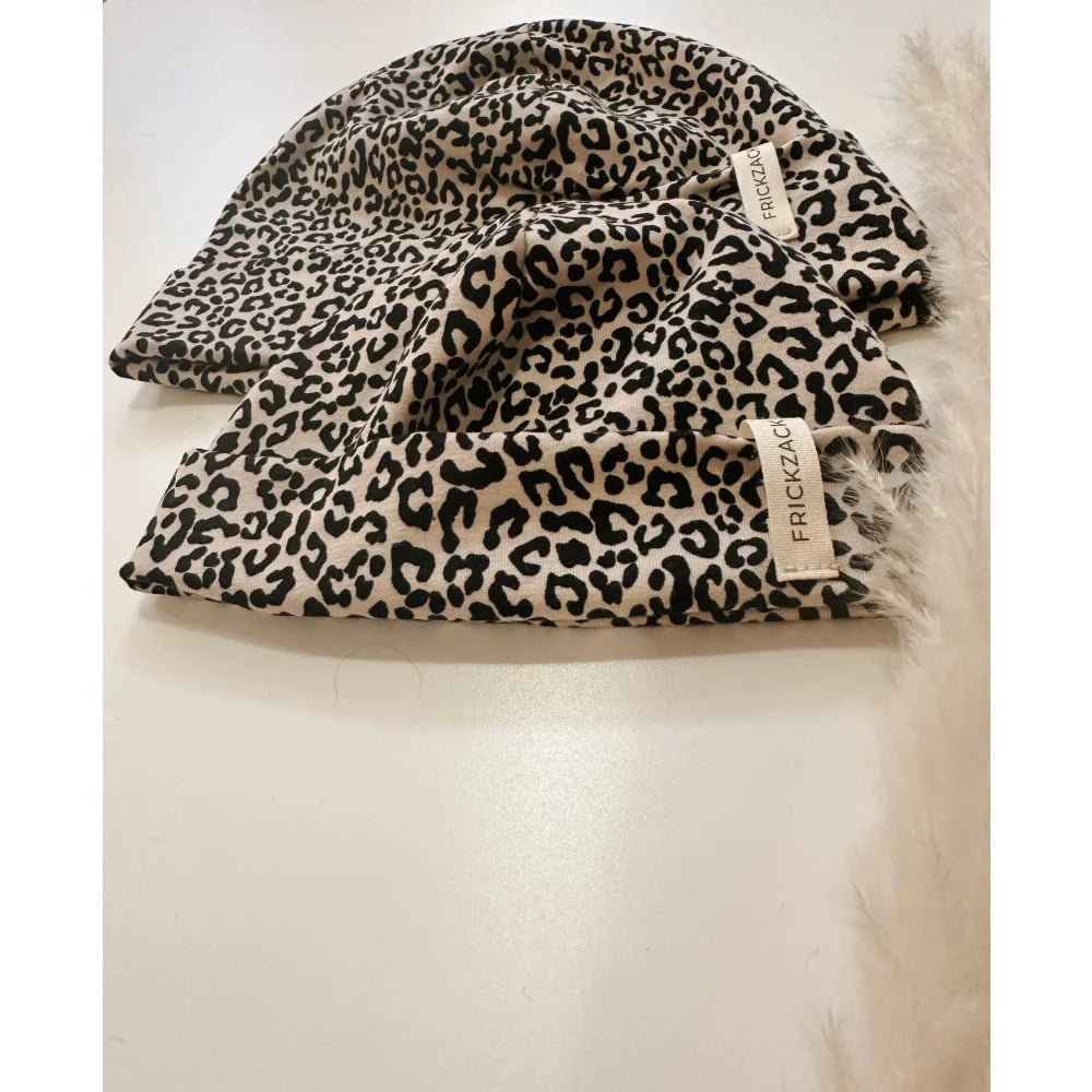 Zwei Leopardenmuster Beanies mit hellbraunen Labels auf dem Produkt Beanie leo