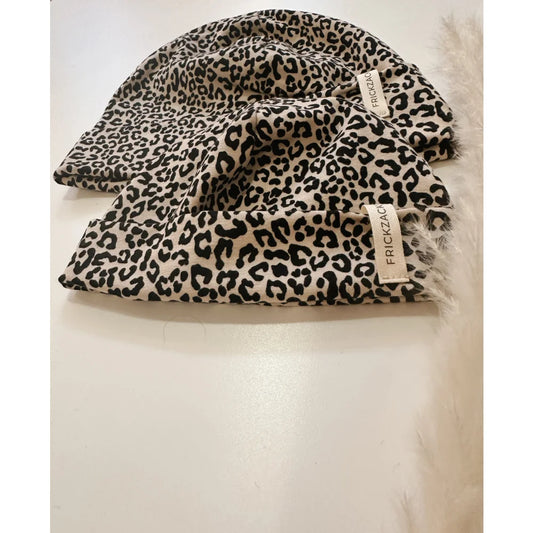 Zwei Leopardenmuster Beanies mit hellbraunen Labels auf dem Produkt Beanie leo