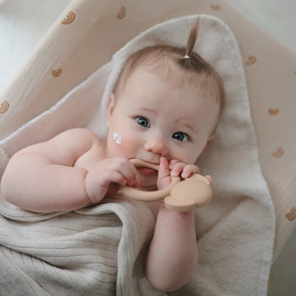 Baby in white towel with hands near mouth, promoting Beissring Hund