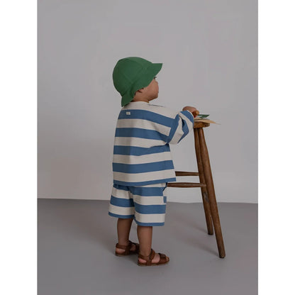 A child wears bermudas deck chair stripes blue and white striped cotton set with brown sandals and green cap