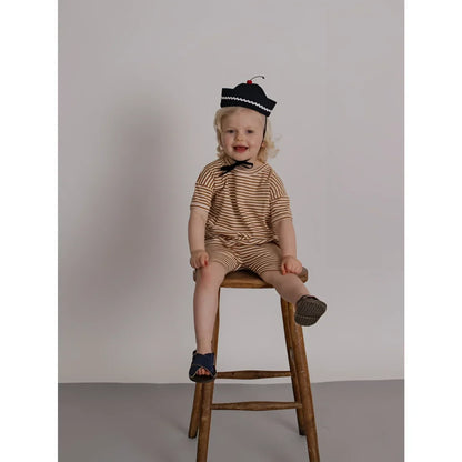 Kind auf Rückenansicht in Biker Shorts Copper Stripes, beige-braun gestreift, marineblaue Sandalen