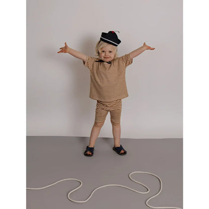 Kind in Biker Shorts Copper Stripes, gestreift braun-beige, marineblauer Hut