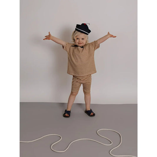 Kind in Biker Shorts Copper Stripes, gestreift braun-beige, marineblauer Hut