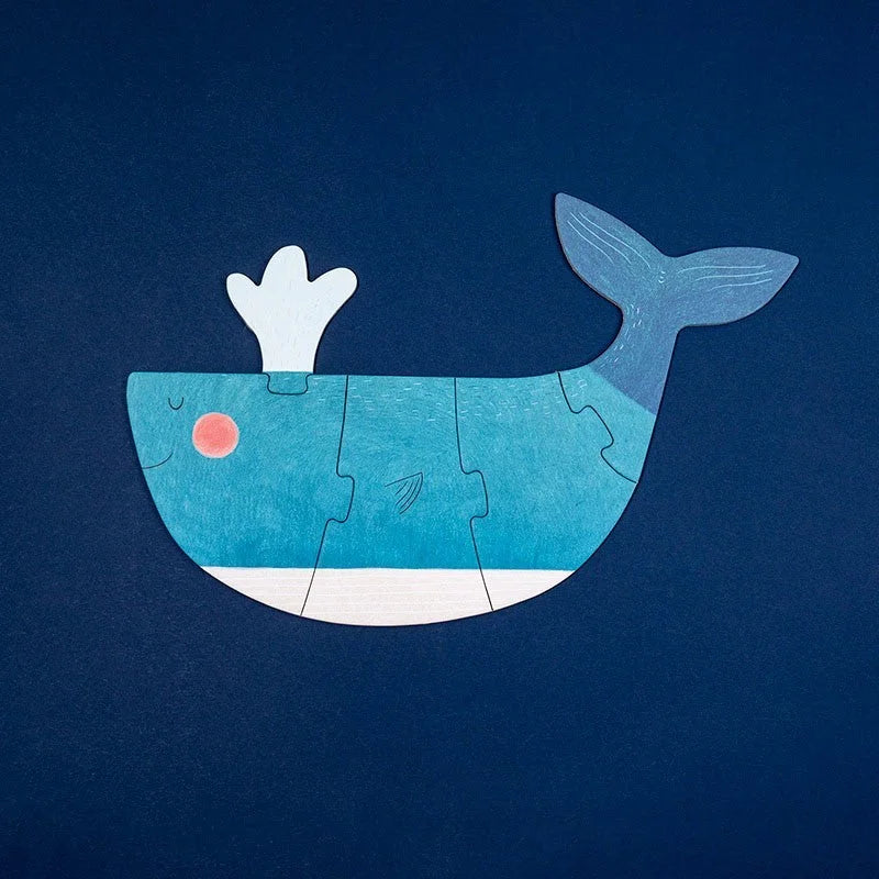 Blaues Puzzle: Türkis-weiße Wal-Jigsaw mit pinkem Auge auf dunklem Blau